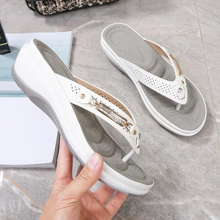 Women's orthopedic flip-flop sandals in white with perforated upper and contoured footbed held in hand