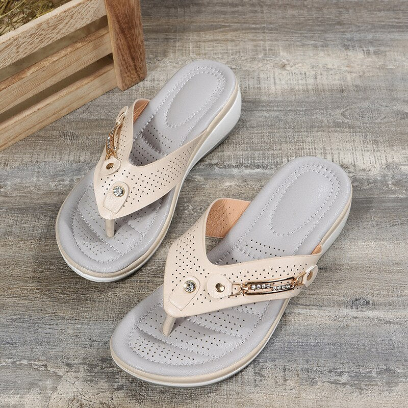 Close-up of women's orthopedic flip-flop sandals showing decorative metal hardware and cushioned insole detail