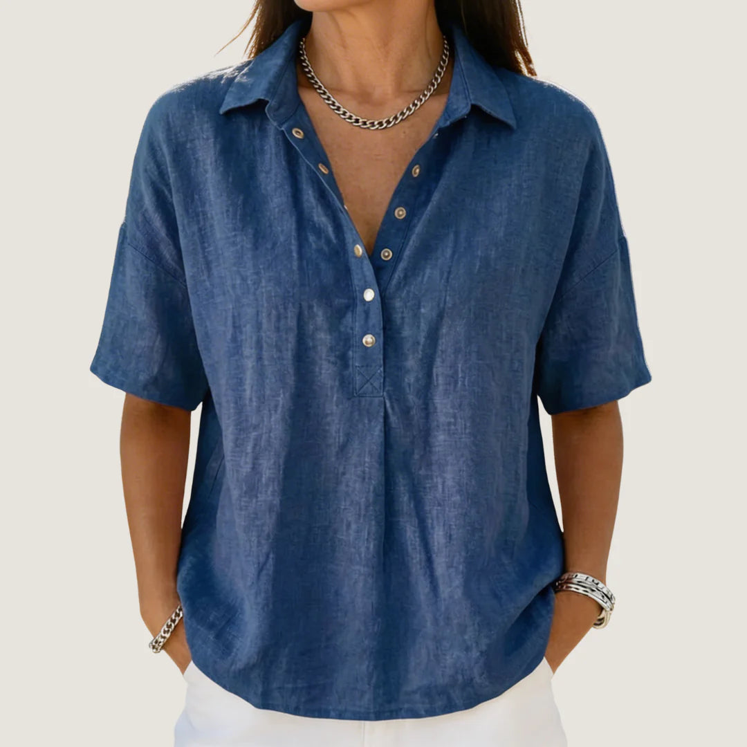 Woman wearing a blue casual button-up collar shirt with short sleeves and relaxed fit, styled with white trousers