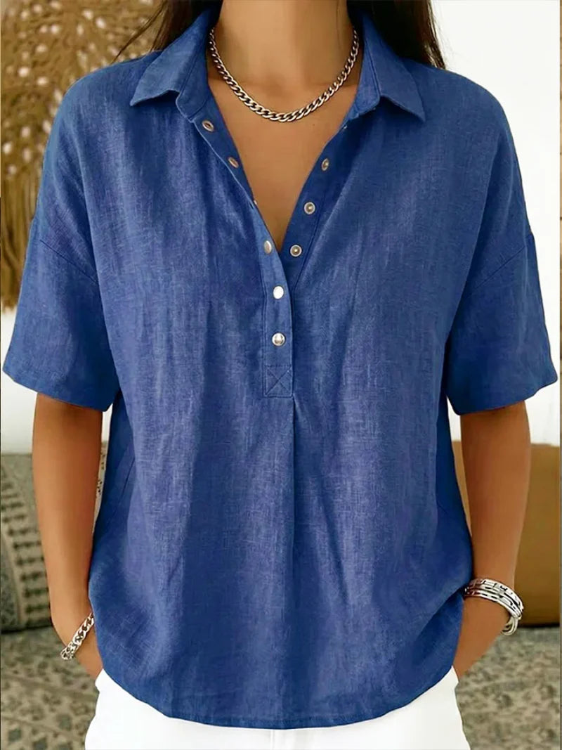 Side profile of a woman in a relaxed-fit blue button-up collar shirt showing the drape and short sleeves