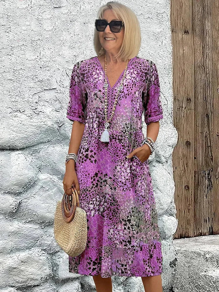Woman styling printed V-neck midi dress with woven bag and sandals for casual summer look