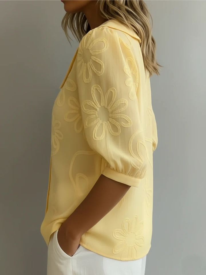 Close-up view of tonal floral embroidery detail on women's yellow blouse