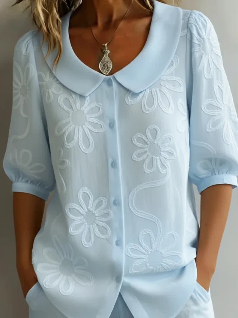 Back view of women's embroidered floral blouse with gathered sleeve cuffs