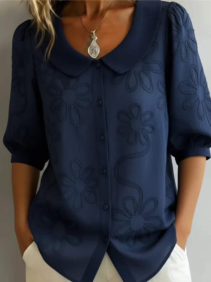 Detail of button-front closure and rounded collar on women's embroidered blouse
