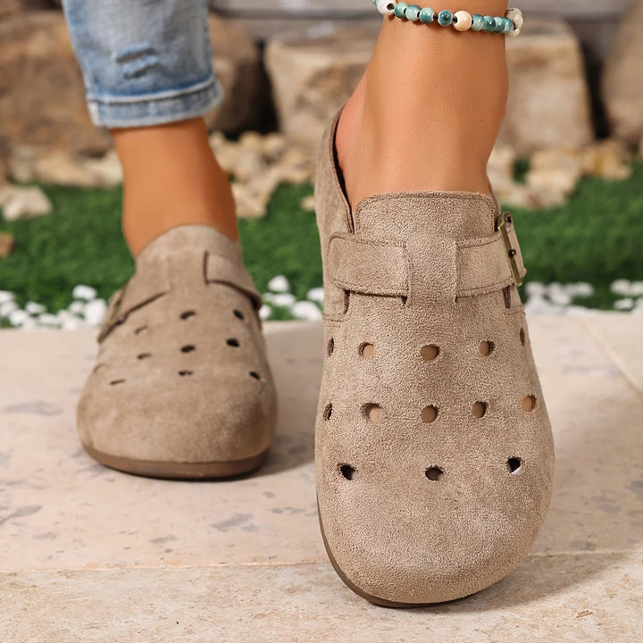 Cecily wearing beige everyday comfort garden clogs with perforated vamp and adjustable heel strap on outdoor patio