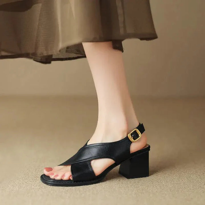 Charlotte wearing Women's Fisherman Sandals Leather Crossover Low Block Heel in black with gold-tone buckle and square open toe