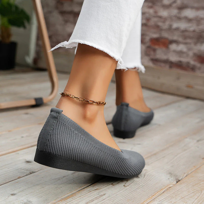 Women's grey knit slip-on flats showing slip-resistant outsole and structured upper