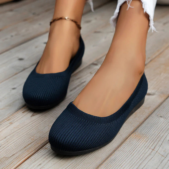 Women's grey knit flats on wooden surface highlighting rounded toe and slip-on style