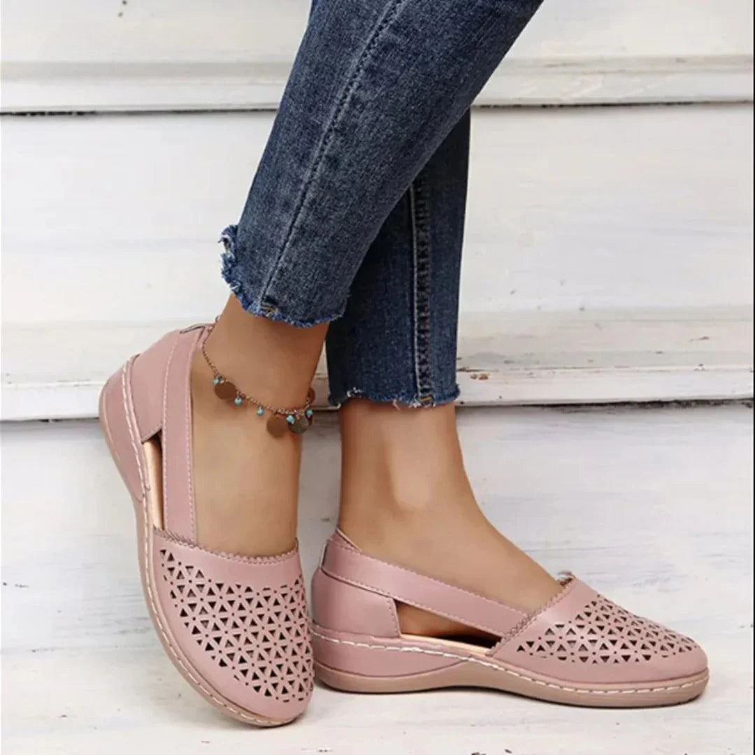 Women's perforated flats in blush pink with geometric cut-out detailing and cushioned footbed, worn with cropped denim jeans