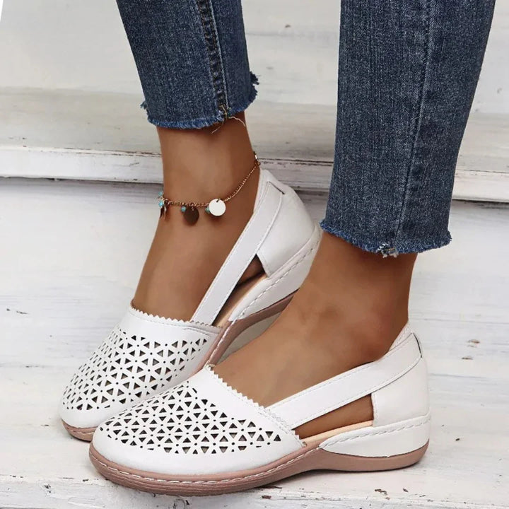 Close-up of women's slip-on flats showing elasticated side panels and decorative perforated vamp design
