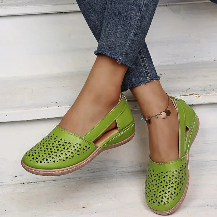 Side view of women's perforated flats displaying low supportive footbed and contrast stitching detail