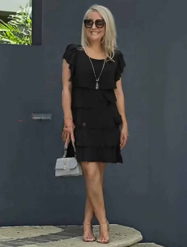 Tiered midi dress styled for daytime event with minimal accessories and natural lighting