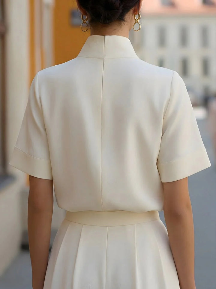 Detail of architectural stand collar with subtle split neckline on women's tailored blouse