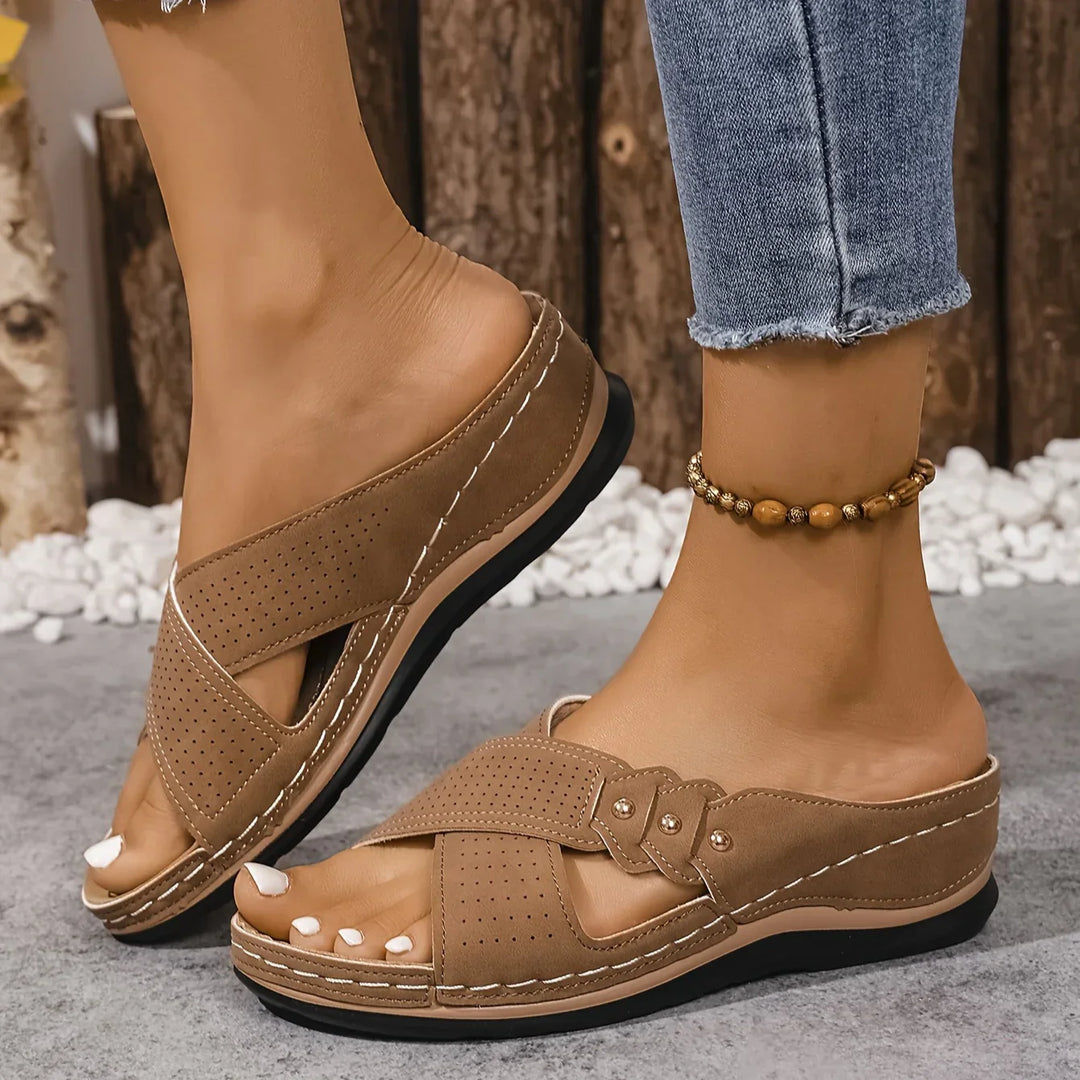 Women's wedge sandals in navy blue on textured outdoor surface showing sole grip pattern