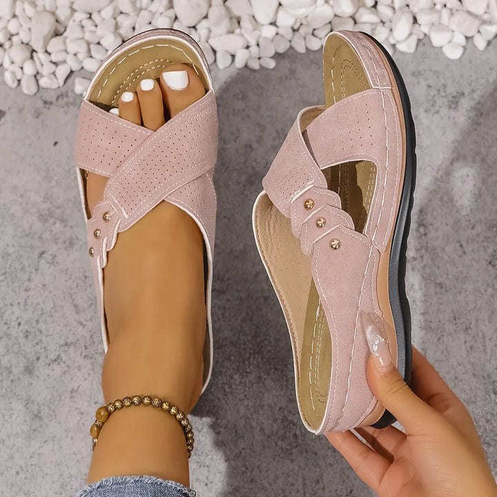 Women's navy wedge sandals worn outdoors on pebbled surface with casual styling