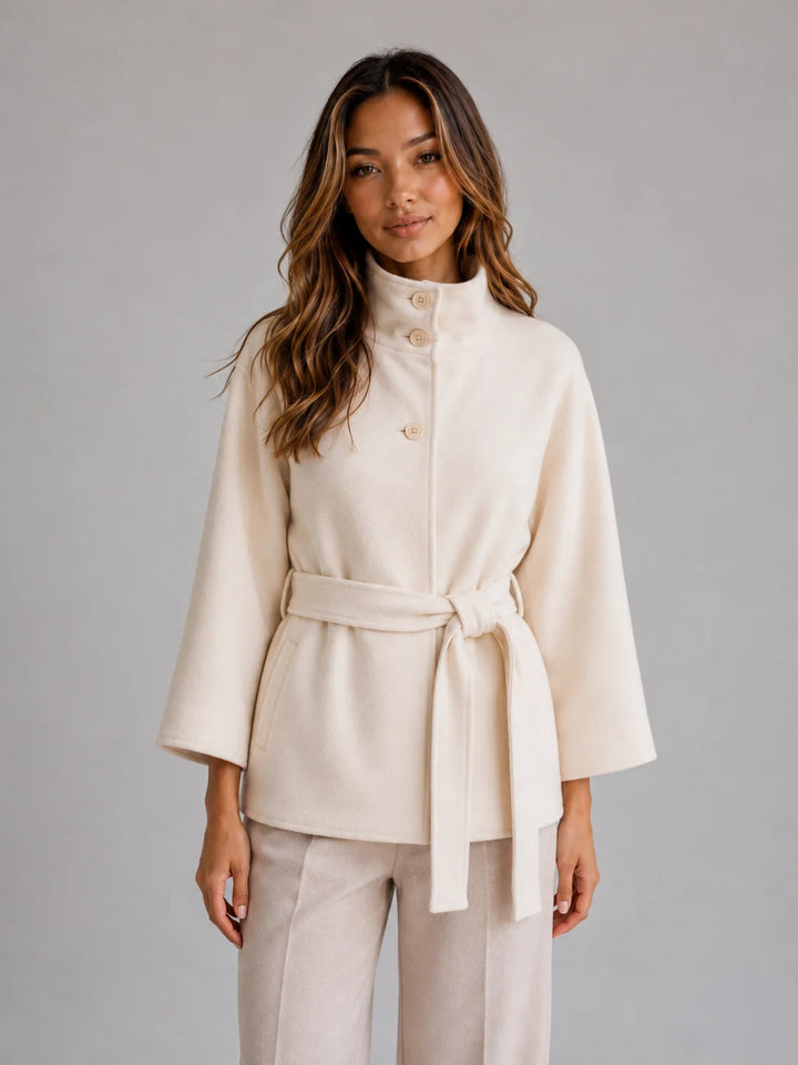 Close-up of stand collar and button detailing on cape jacket in smooth woven fabric