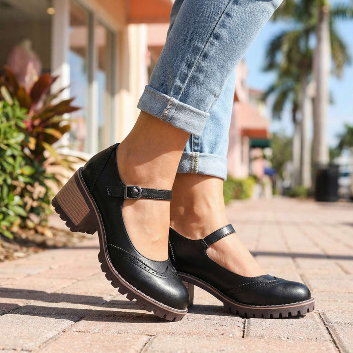 Women's T-strap block heel shoes in black with brogue detailing and chunky tread sole worn outdoors
