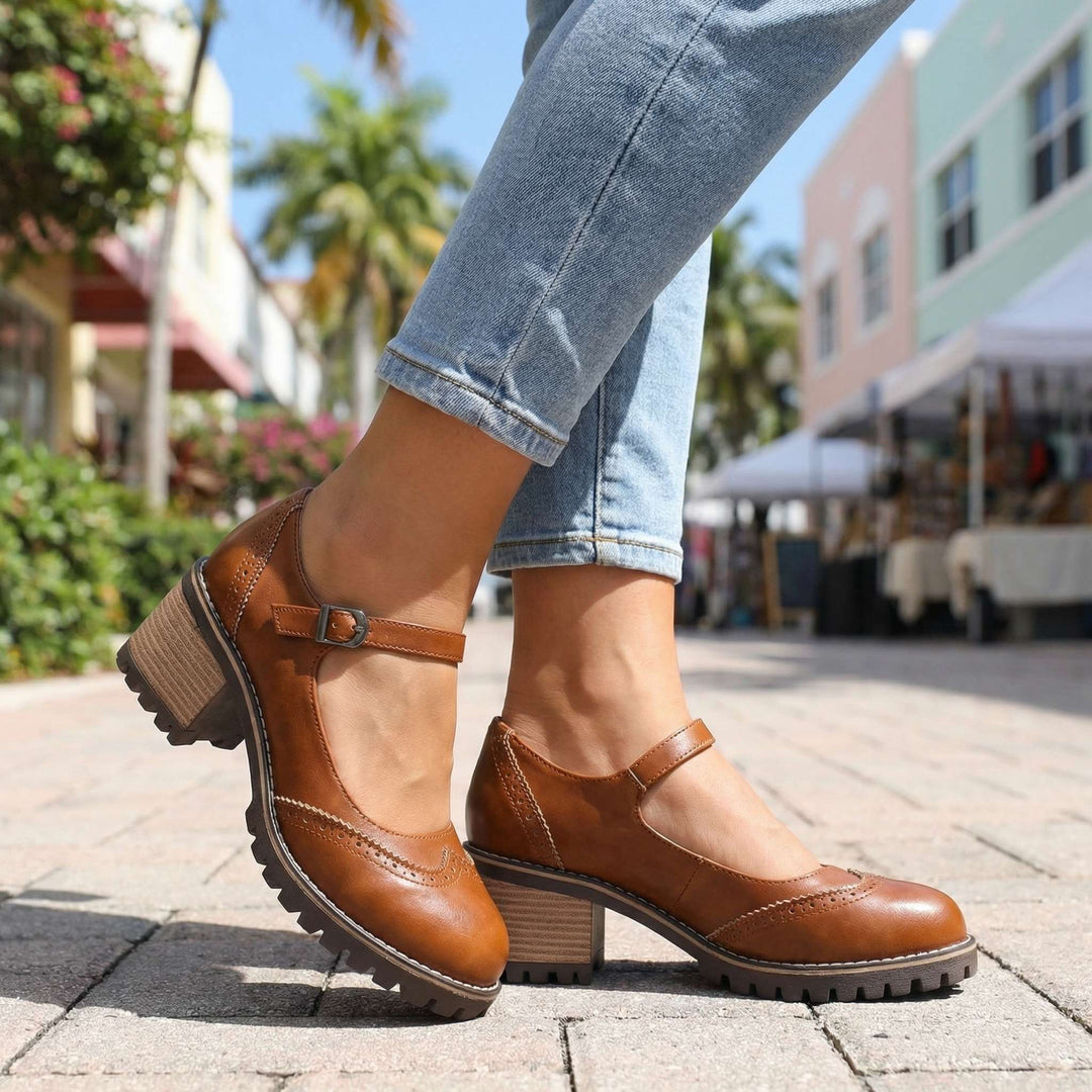 Close-up view of women's black T-strap block heel shoes showing ankle buckle and perforated brogue pattern