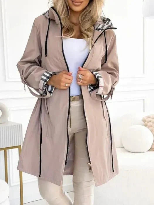 Close-up of women's trench coat showing full zip closure and front patch pockets