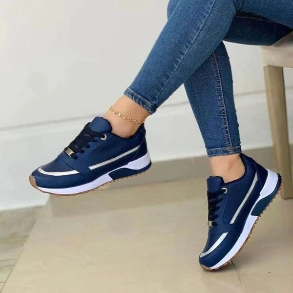 Women's trainers in navy with white contrast stripe and cushioned sole worn with jeans