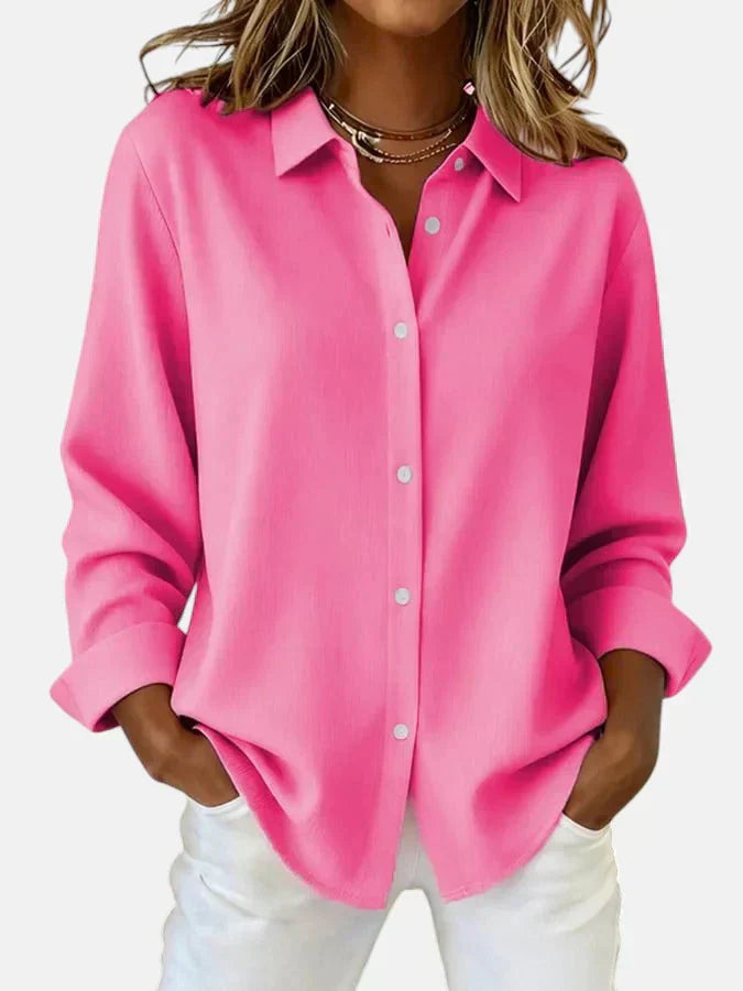 Women's oversized shirt in bright pink with classic collar and button-front closure worn with white trousers