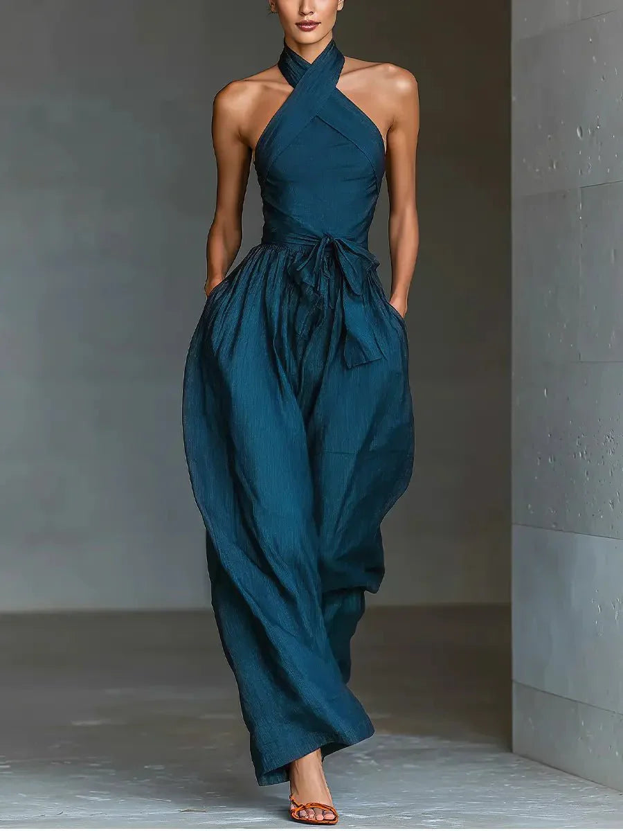 Halter neck wide-leg jumpsuit in deep teal with cross neckline and flowing silhouette worn by model