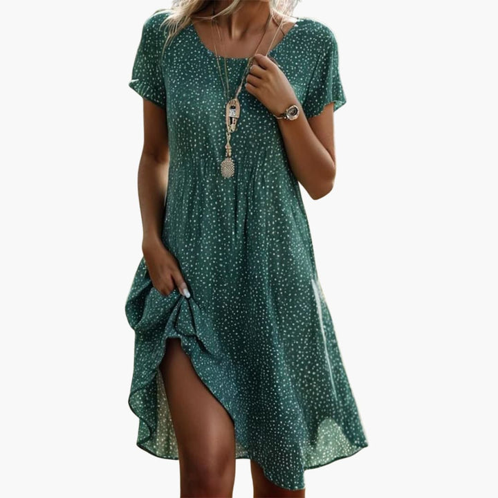 Side view of navy polka dot midi dress displaying A-line silhouette and front slit hem