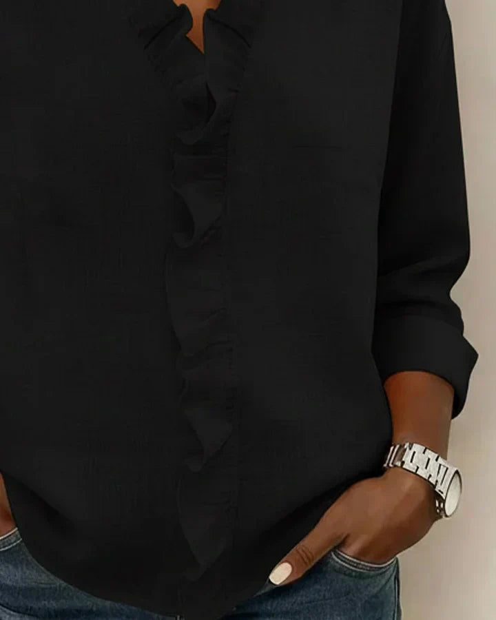 Detail of long sleeves on women's ruffle neck blouse with rolled cuffs