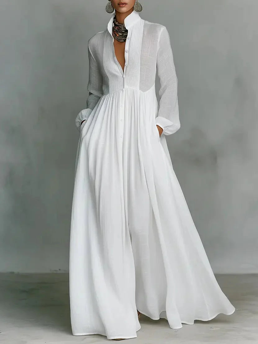 White maxi dress with stand-up collar and flowing skirt worn with statement earrings