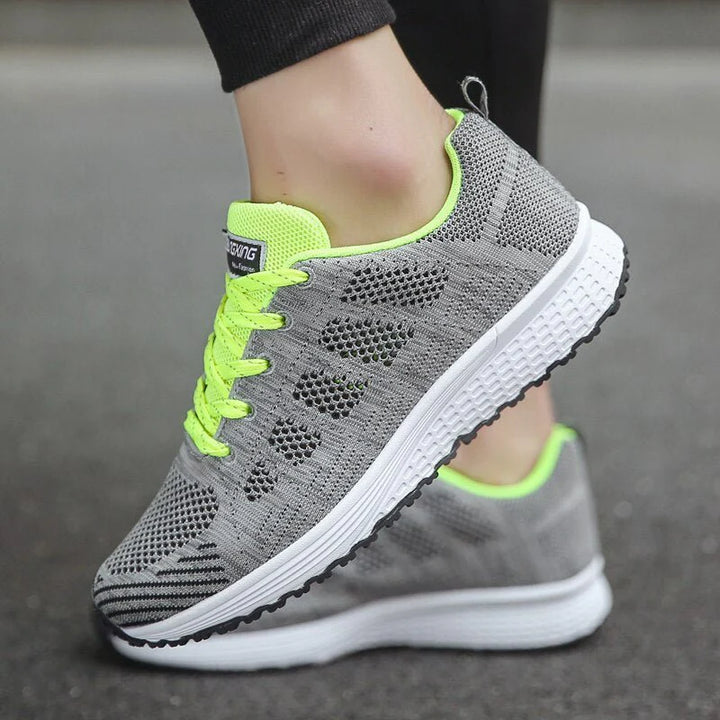 Side profile of women's white trainers showing supportive structure and breathable knit