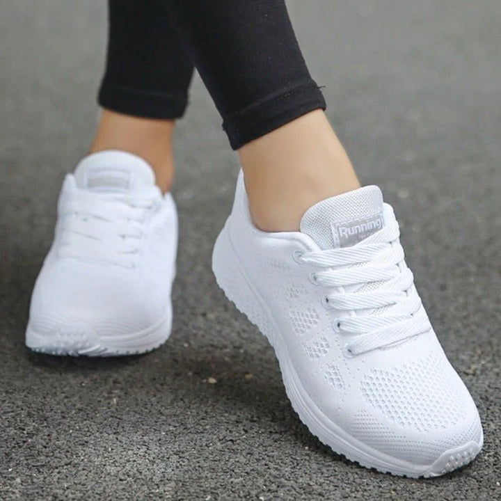 Side view of women's white mesh trainers showing breathable knit upper and lace-up closure