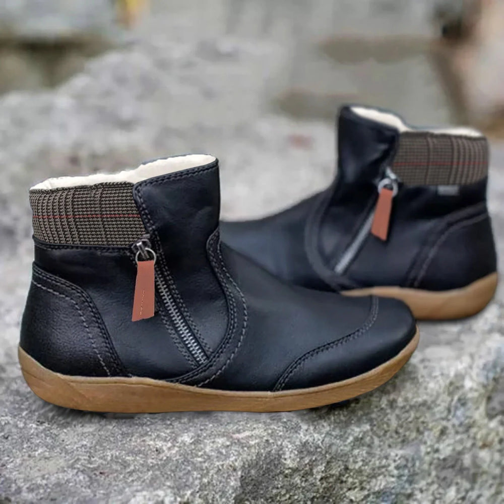 Close-up view of ankle-height waterproof boots showing structured material and decorative zip detail