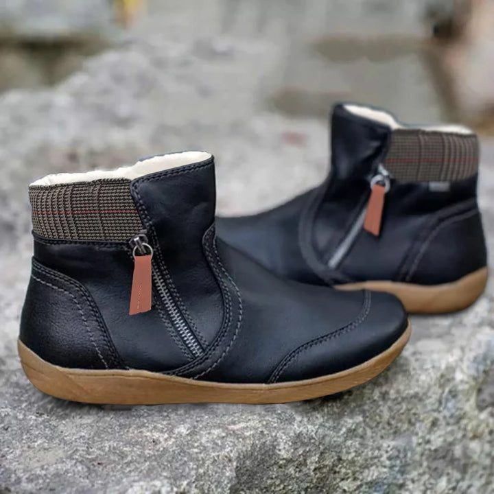 Close-up view of ankle-height waterproof boots showing structured material and decorative zip detail
