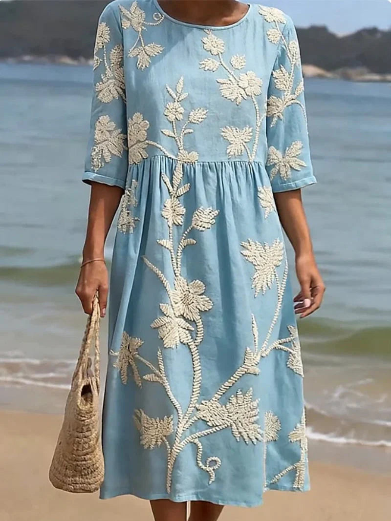 Close-up view of textured floral embroidery detail on midi dress bodice and sleeves