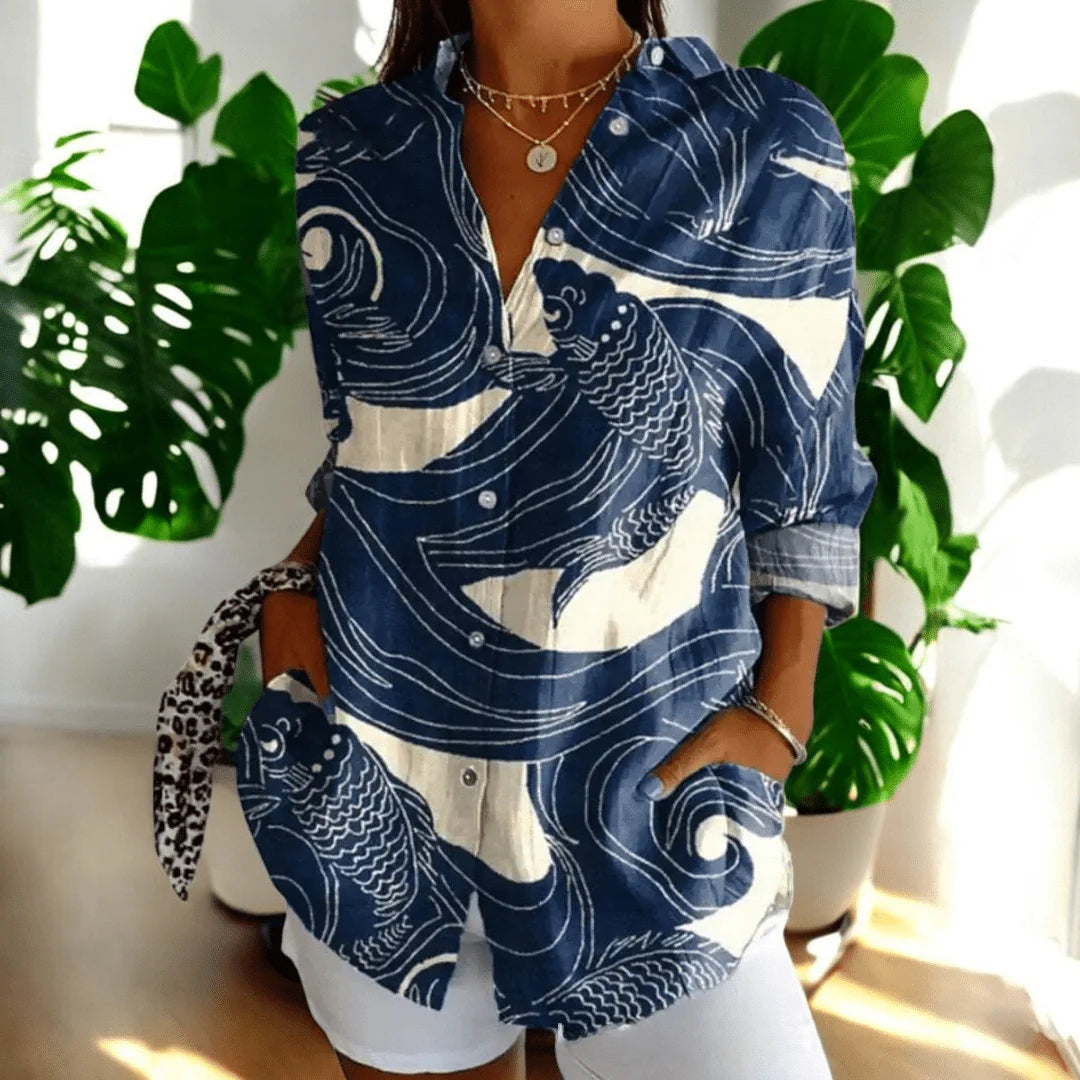 Close-up of women's floral blouse showing vibrant coral and pink hibiscus print on dark base
