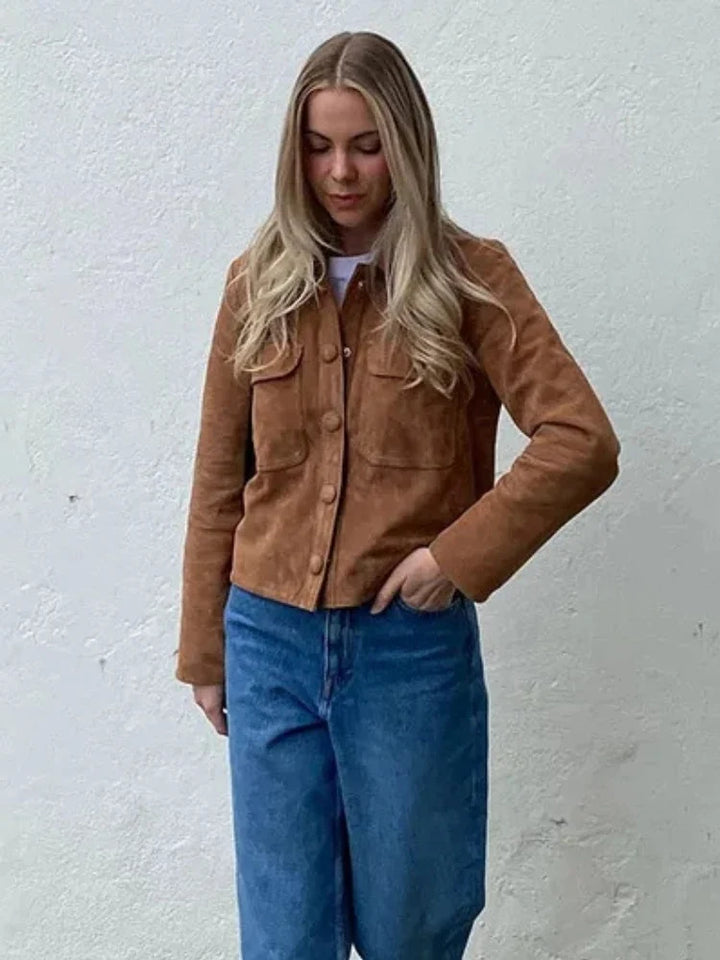 Women's suede shirt jacket in tan with chest pockets and button-through front worn with jeans