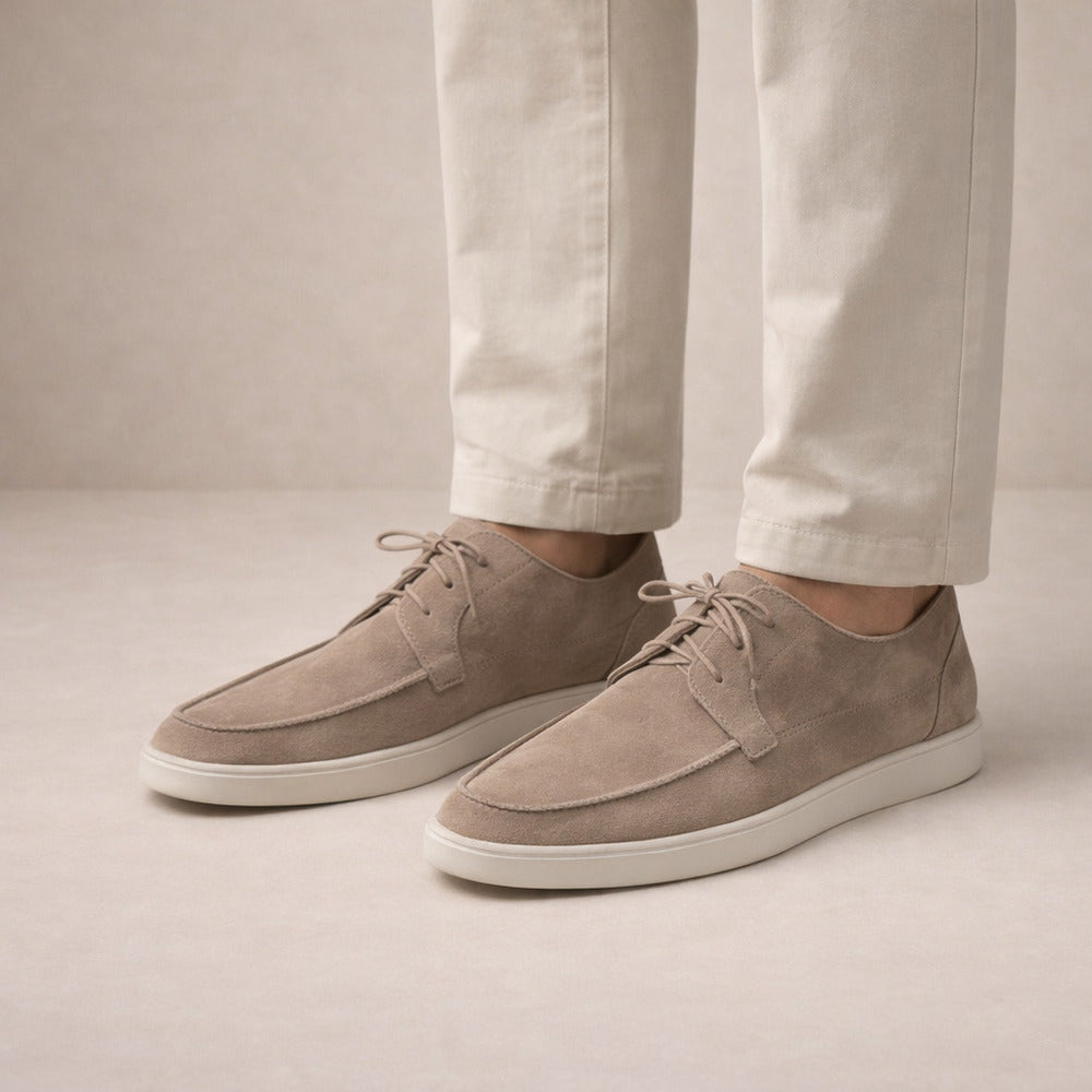 Men's lace-up moc-toe shoes in taupe, worn on model with cream trousers