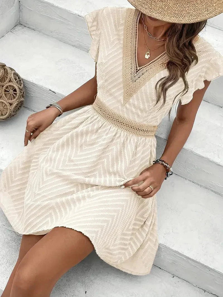Woman styling v-neck mini dress with straw bag and layered gold necklaces