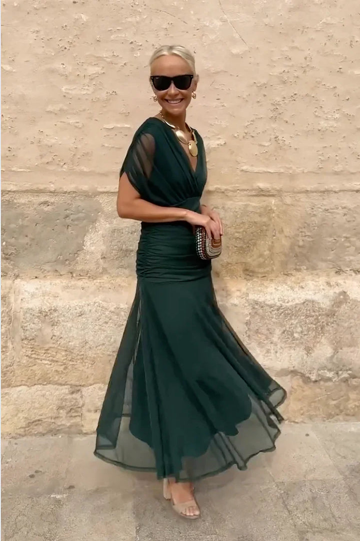 Detail view of ruched waist and skirt layers on emerald V-neck maxi dress