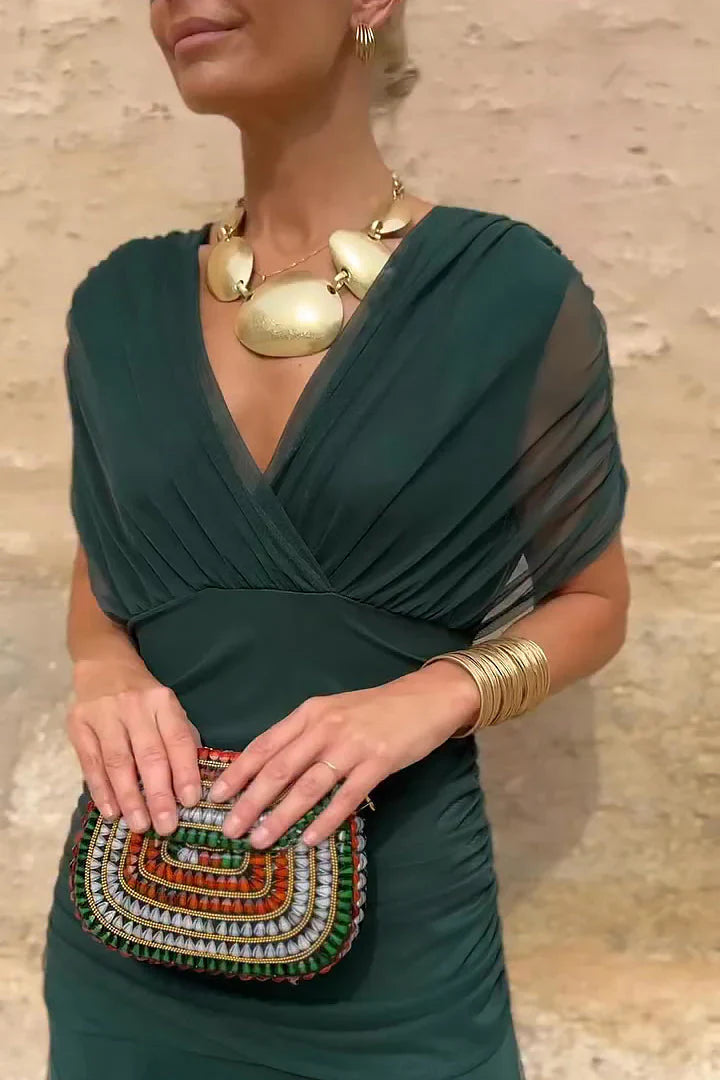 Side view of emerald maxi dress displaying flowing layered skirt and gathered waist silhouette