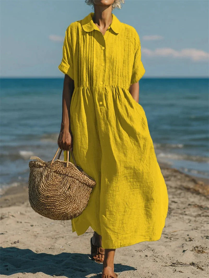 Woman in white collared dress walking on beach in casual summer styling