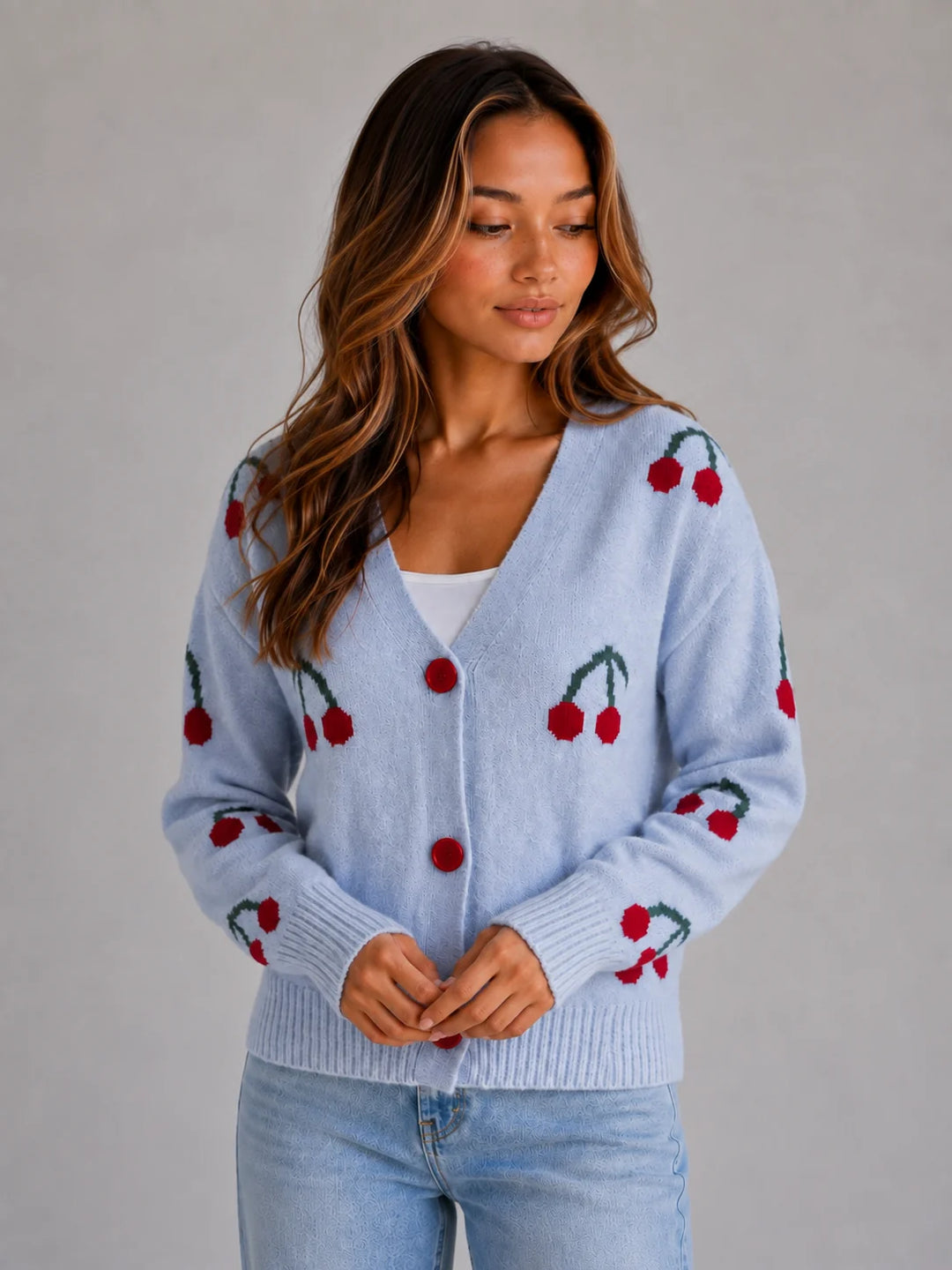 Close-up of button front fastening and cherry motif on women's V-neck cardigan