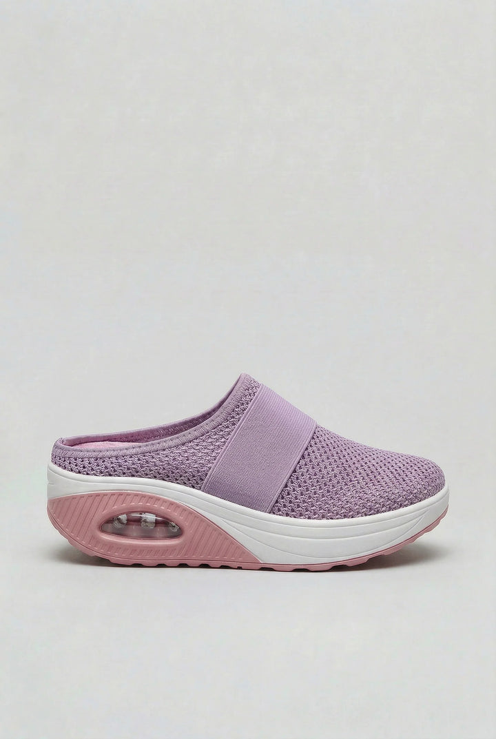 Women's mules in beige featuring slip-on design and curved rocker outsole for natural movement