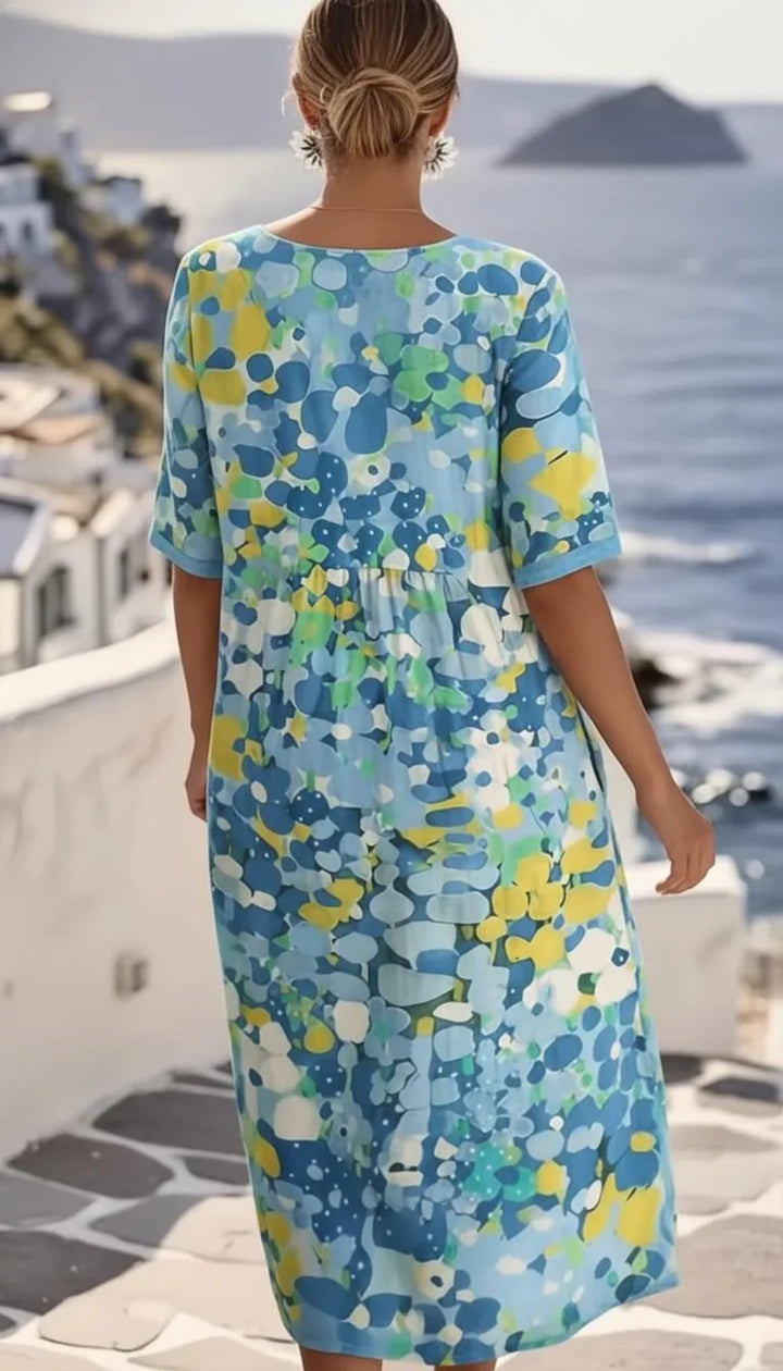 Full-length abstract print midi dress styled with woven basket bag for summer holiday wear