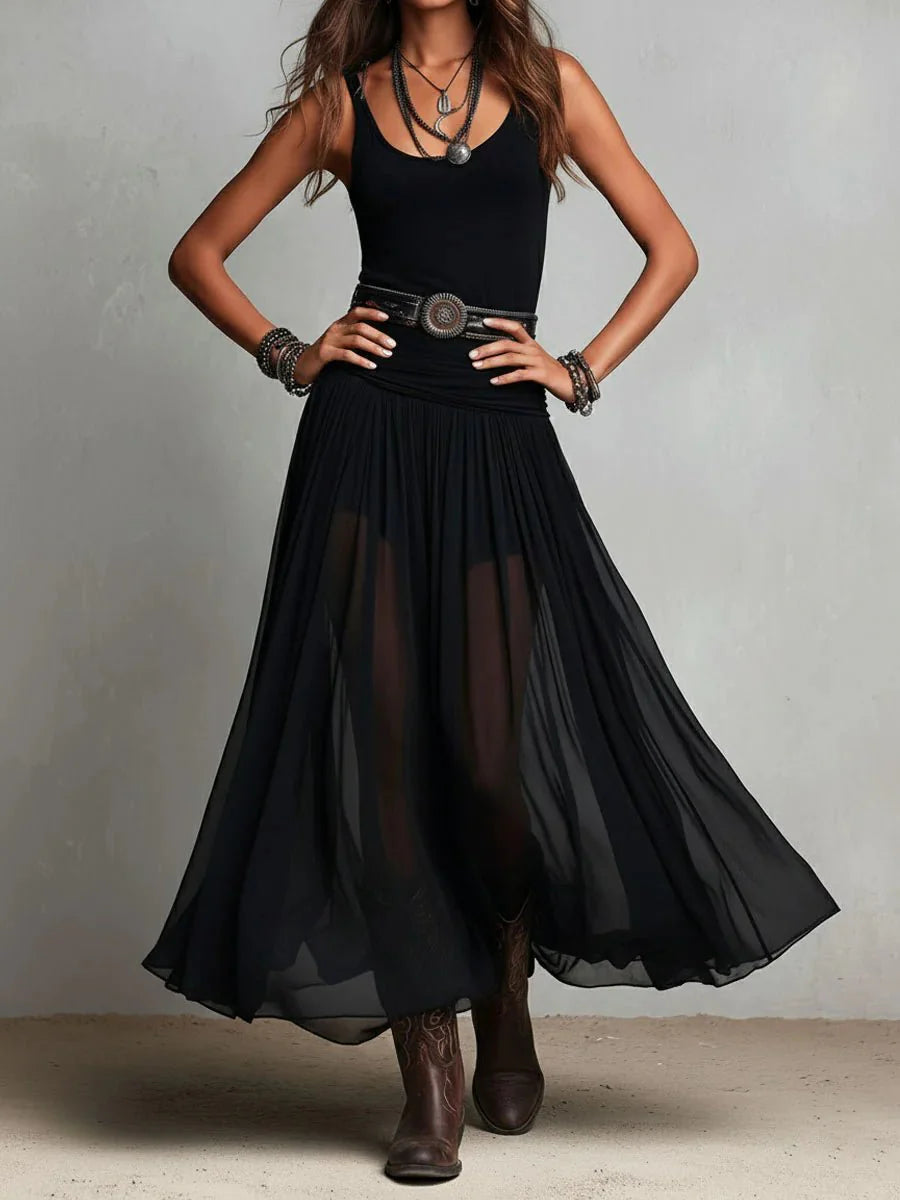 Full-length sleeveless maxi dress with flowing sheer skirt styled with ankle boots