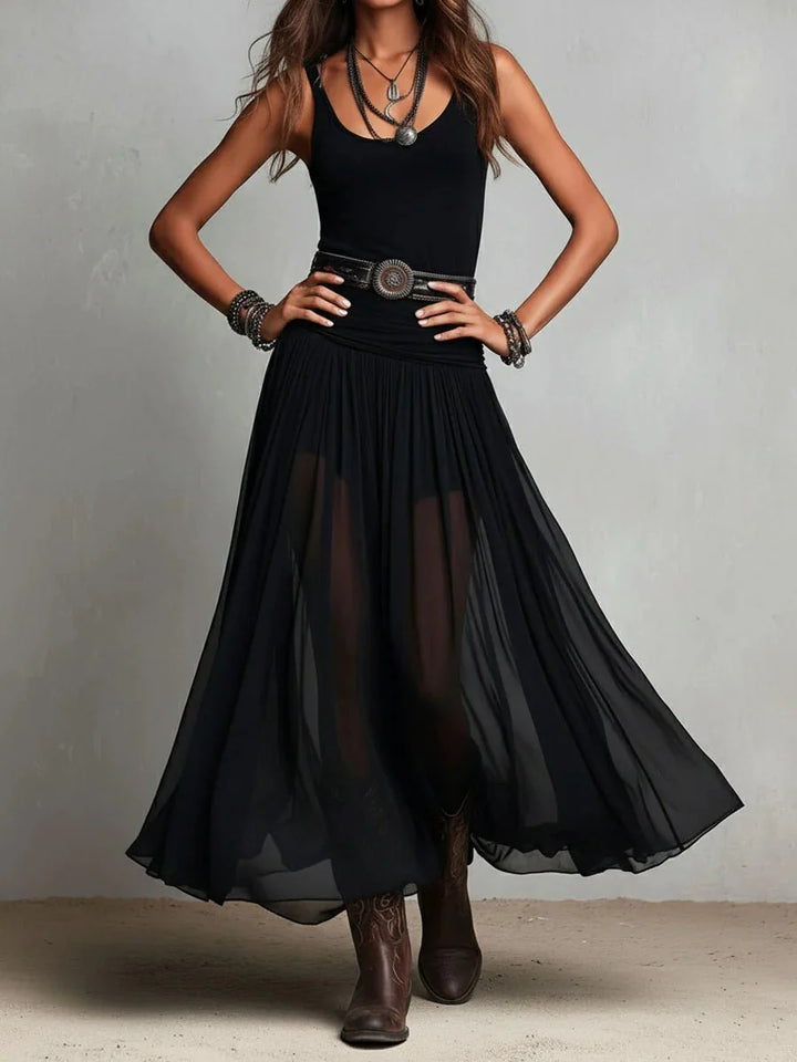 Full-length sleeveless maxi dress with flowing sheer skirt styled with ankle boots