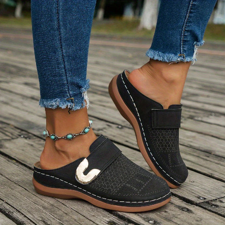 Top view of women's slip-on mules displaying textured upper and gold-tone buckle accent
