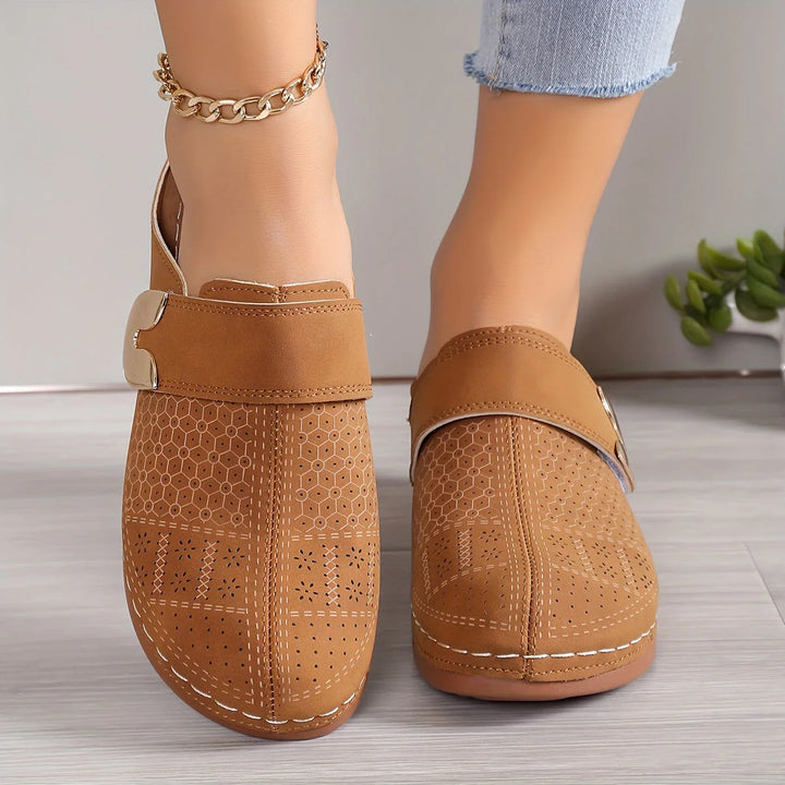 Detail shot of women's slip-on mules highlighting decorative buckle and textured material