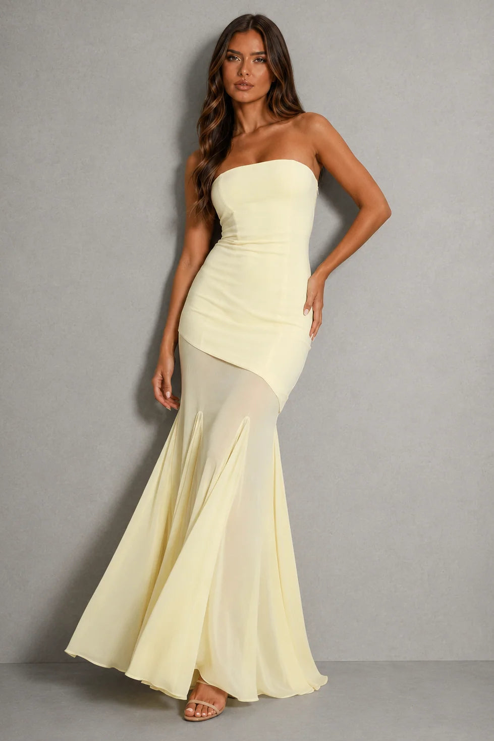 Women's strapless maxi dress with asymmetric hem in pale yellow, featuring sheer overlay and fitted bodice for wedding guest and evening occasions