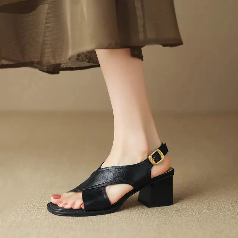 Women's block heel sandals with black leather crossover straps and adjustable gold-tone slingback buckle on model